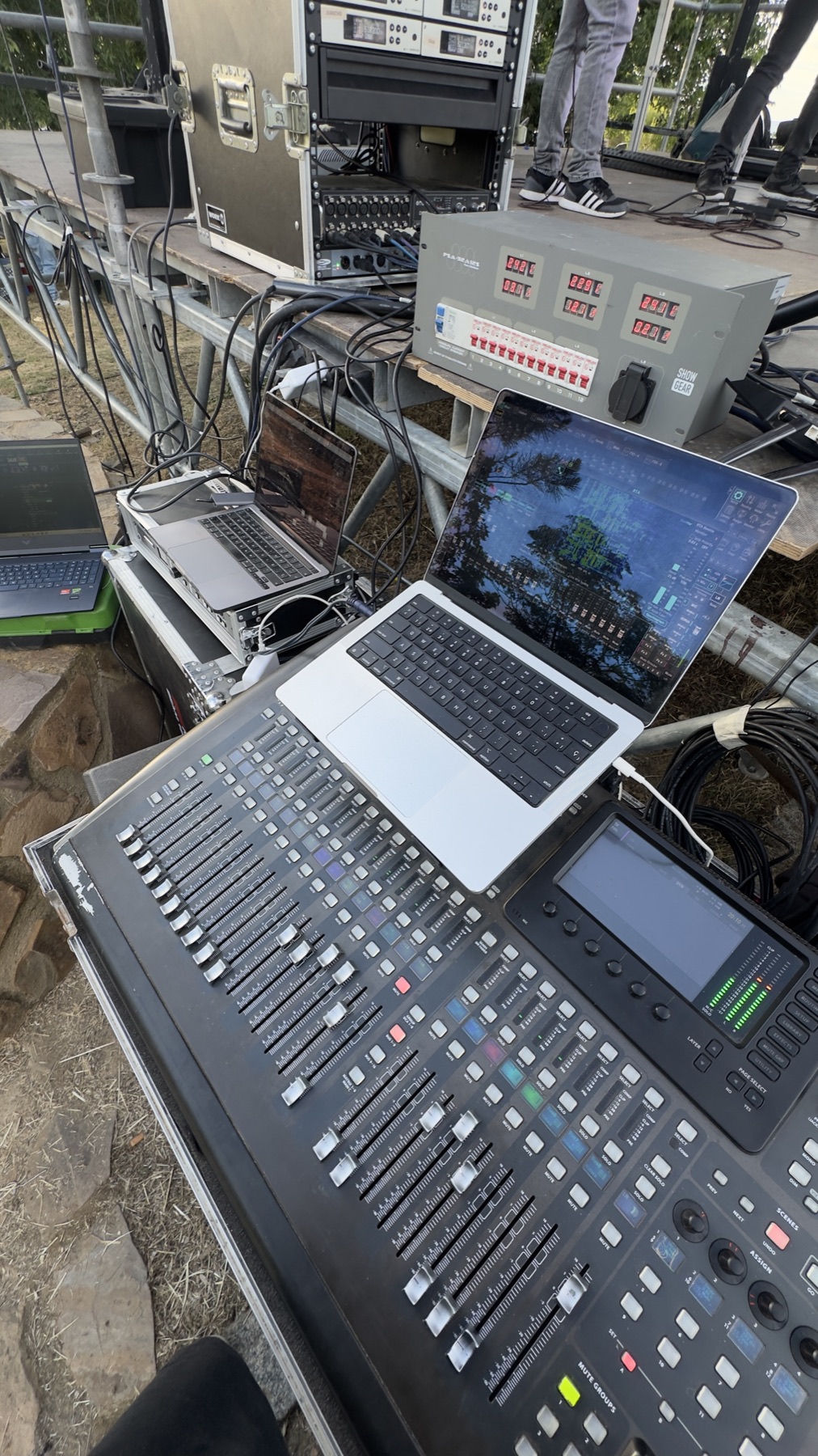 Mesa de FOH con varios portátiles en un festival de día